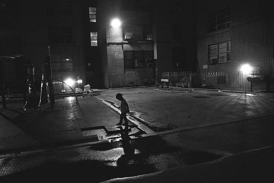 A child walking by a playground at night.