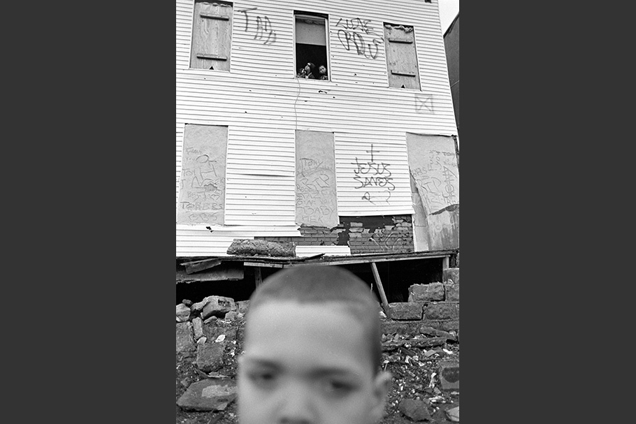 A boy in front of a rundown house.