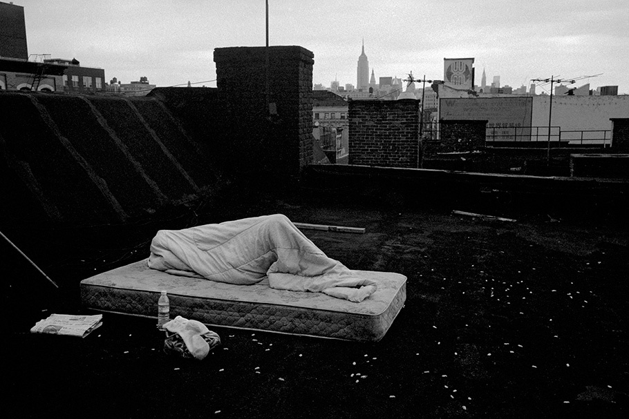A person sleeping on a mattress on a roof.