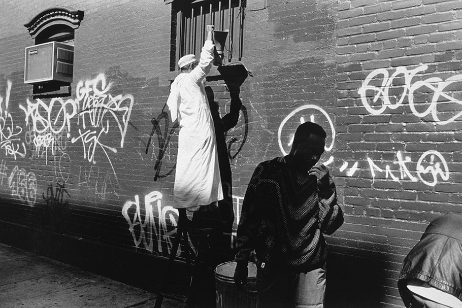 Two men in front of a graffitied wall. 