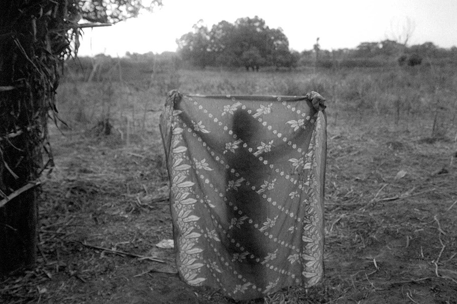 A person silhouetted behind a patterned sheet.