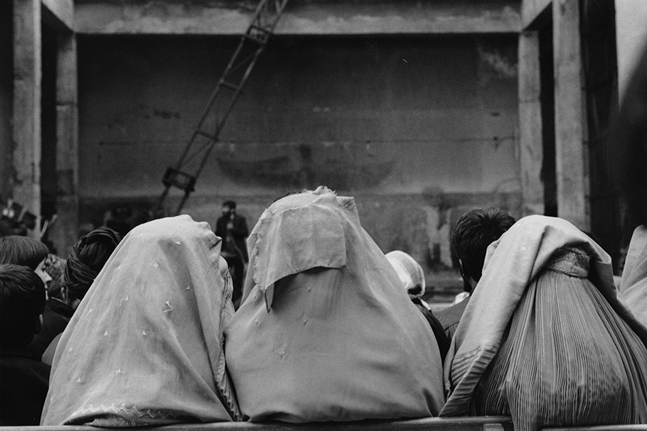 Three women in headscarves at a theater viewed from behind.