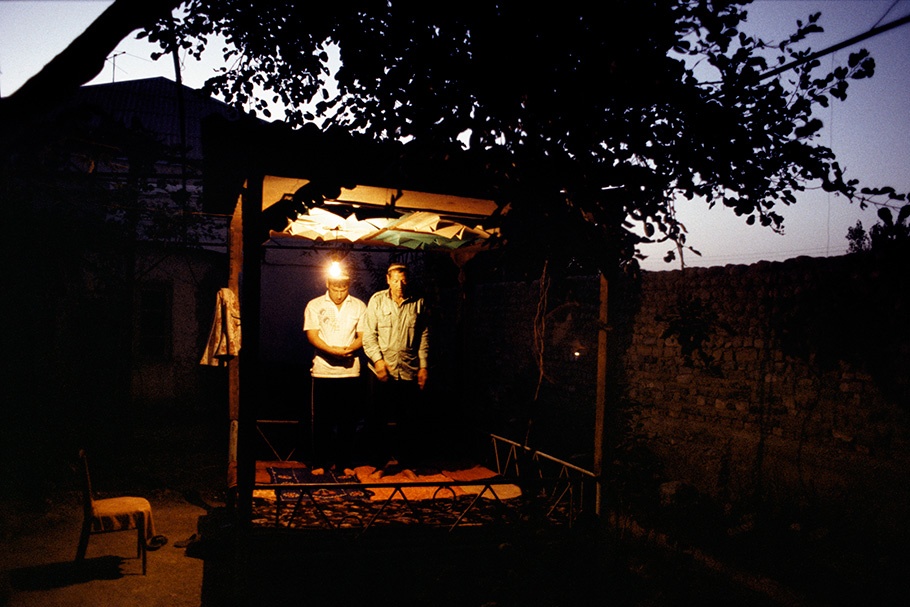 Men praying in an outdoor shelter.