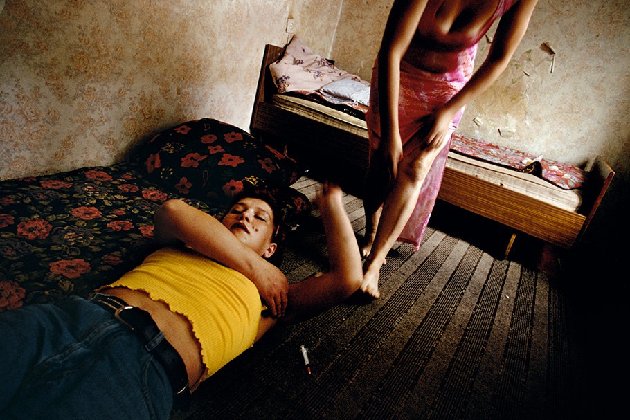 A drug user in yellow lying down in front of another in pink.