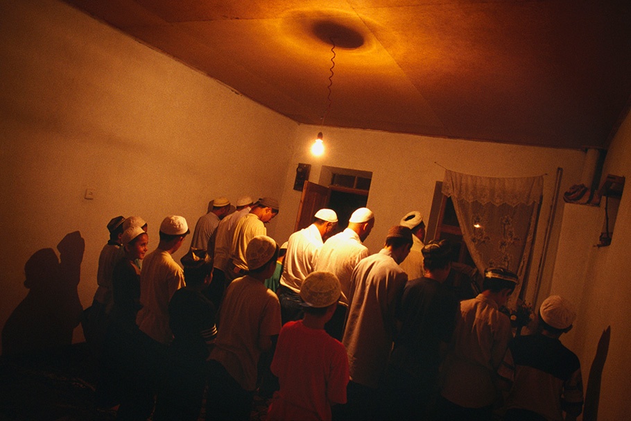 A group of men praying viewed from behind.