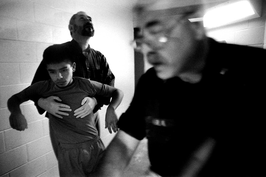 A boy is held up by an officer, with another in the foreground.