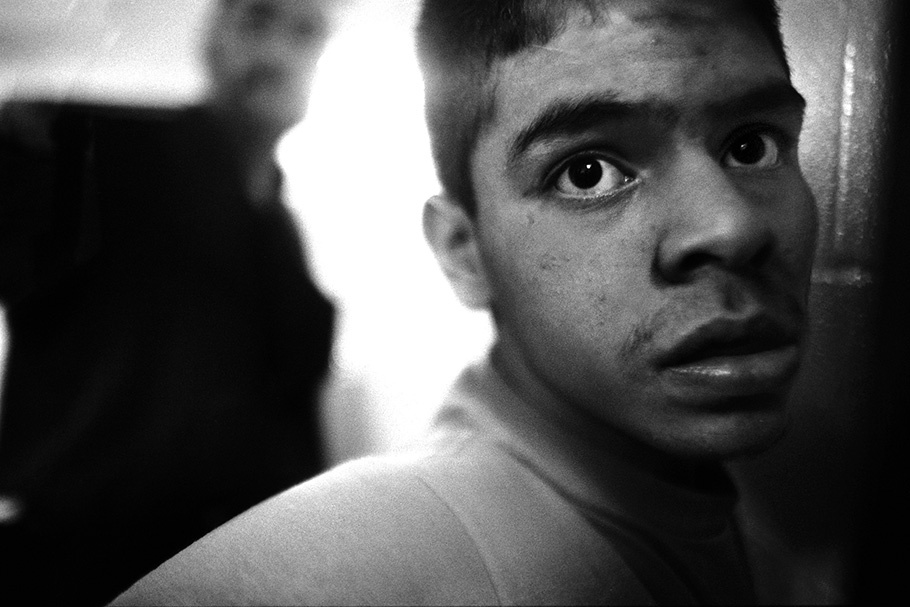 Close up of a boy with a blurred officer in the background.