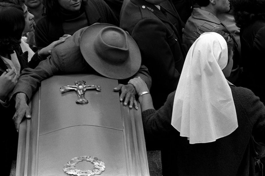 A man draped over a coffin.