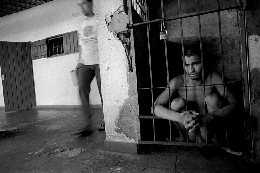 A teenage boy in a small cell behind bars.