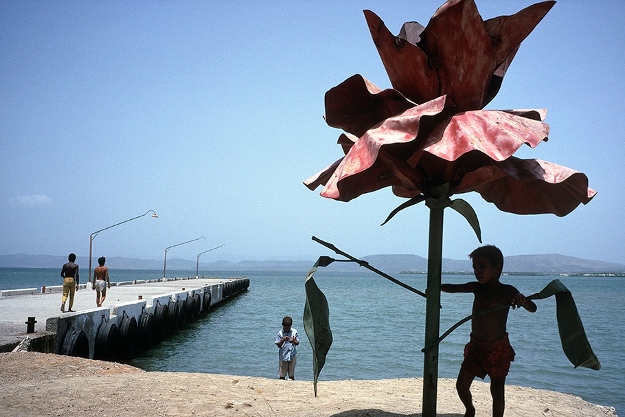 A child playing under a large flower sculpture.