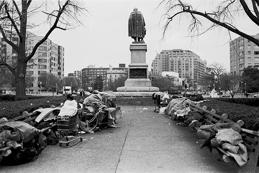 Homeless people in front of a statue.