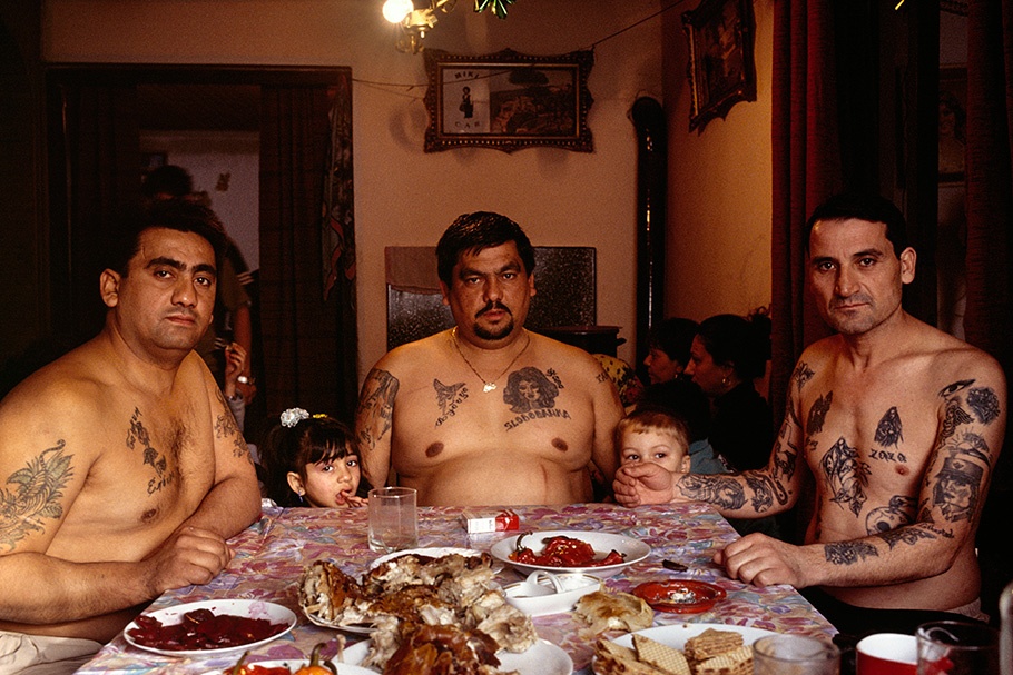 Three tattooed men and two children at a table.