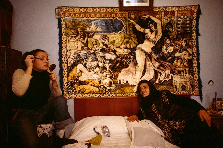 Two women in front of a tapestry.