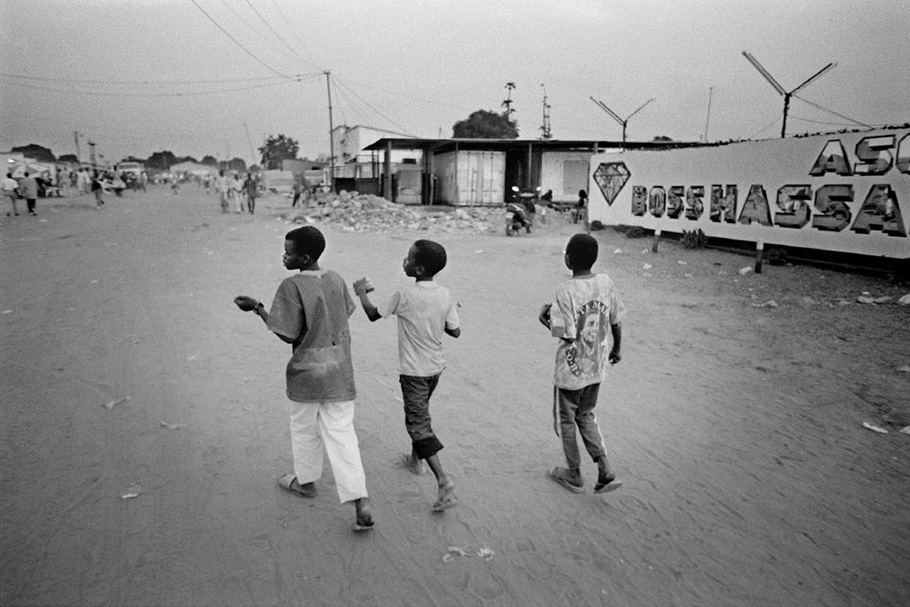 Three children walking in front of a diamond advertisement.