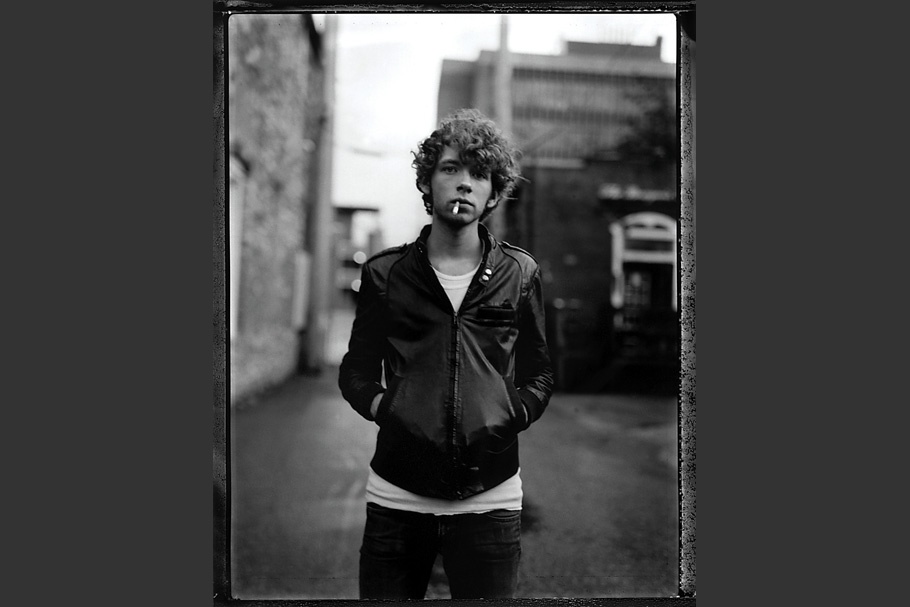 Teenage boy in leather jacket smoking a cigarette.