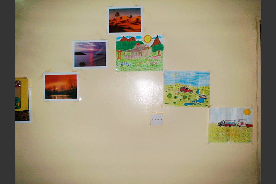 A wall with landscape photographs and children’s drawings.