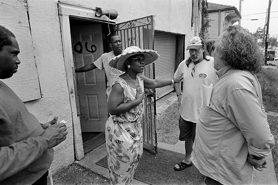 Group of people; woman in hat in front of door.
