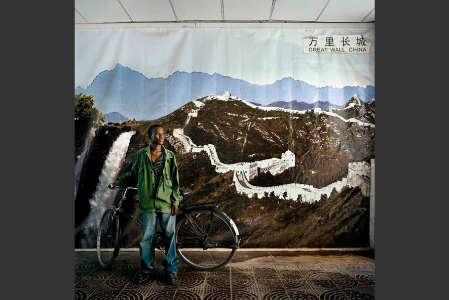 Man with bicycle in front of mountain mural.