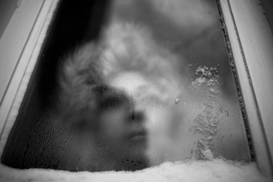 Woman with fur hood seen through a window.