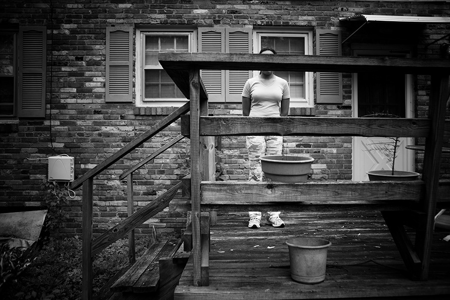 Person posed standing behind the railing of a deck.