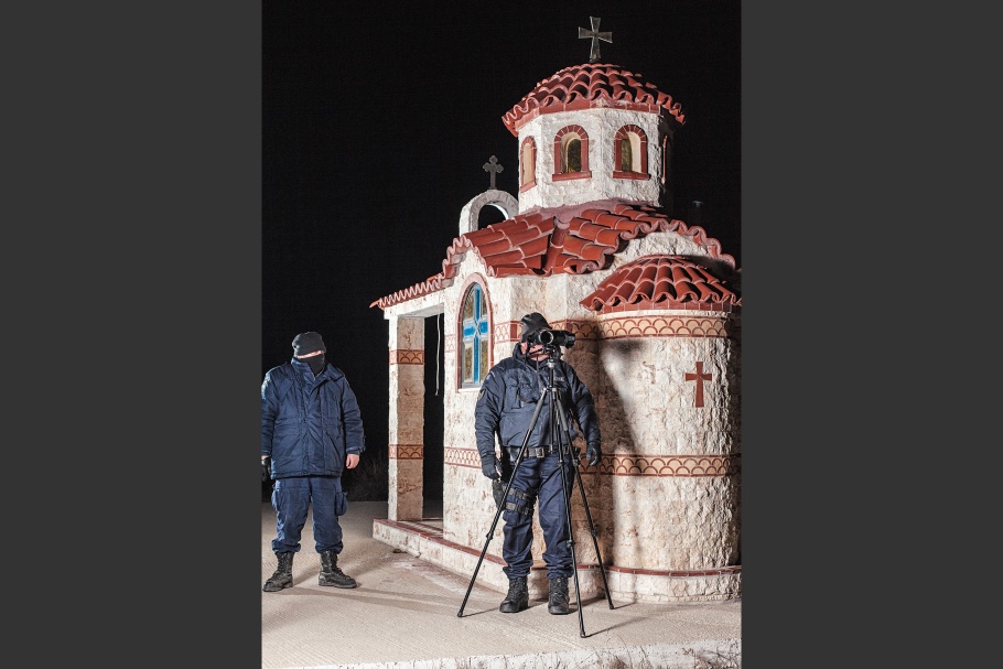 Two border patrol police stand in front of small chapel