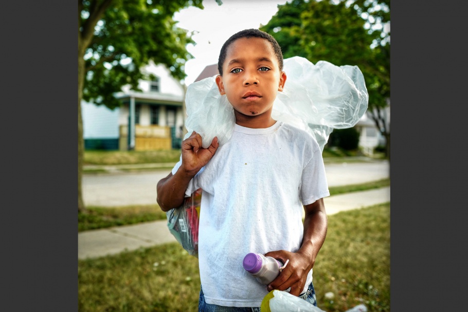 A boy holding a plastic bag over his shoulder.