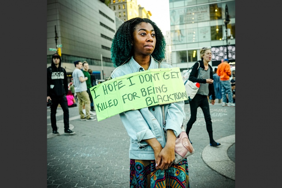 A woman in the street with a sign that says, "I hope I don't get killed for being black today."
