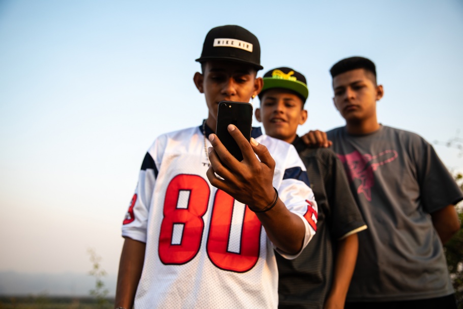Three boys look at a cell phone