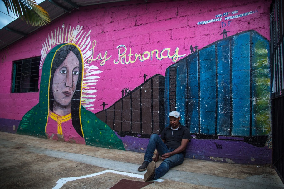 A man sitting down against a mural 