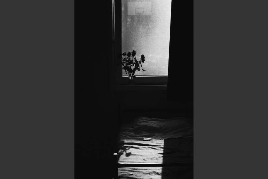 An empty bed with flowers on a windowsill