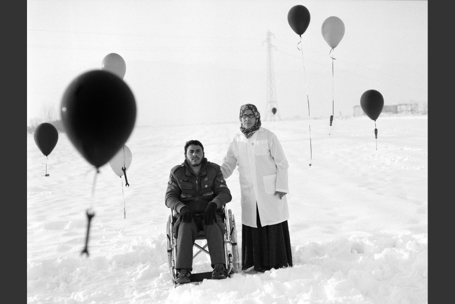 A man in a wheelchair and a woman standing in the snow