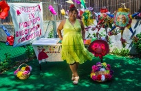 A woman standing in front of a table with piñatas nearby